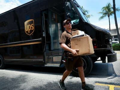 A UPS delivery driver carries packages to their destination