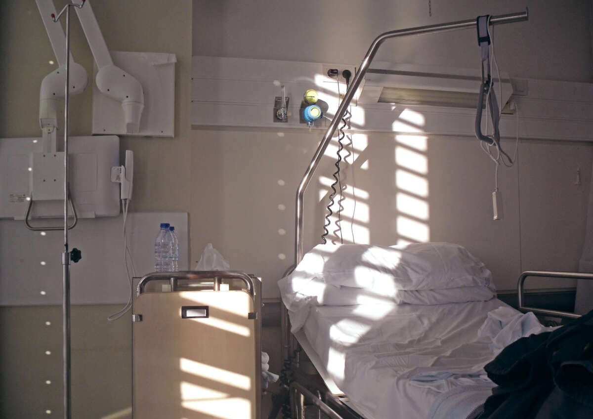 Empty hospital bed with bright day light coming through window blinds