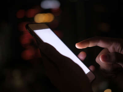 Person using lit-up cell phone in dark area