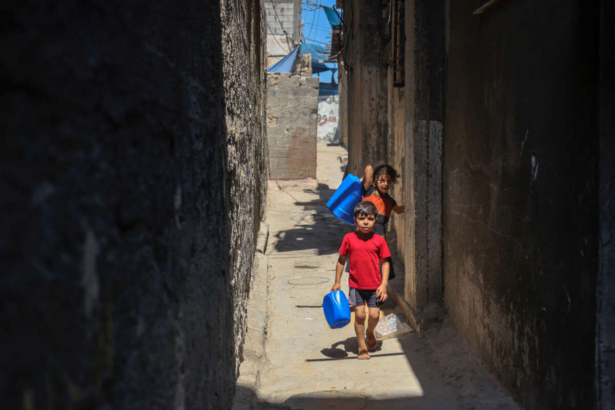 Palestinian children carry water gallons in the Al-Shati refugee camp in Gaza city on July 31, 2023, amidst a heatwave and power cuts.