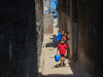 Palestinian children carry water gallons in the Al-Shati refugee camp in Gaza city on July 31, 2023, amidst a heatwave and power cuts.