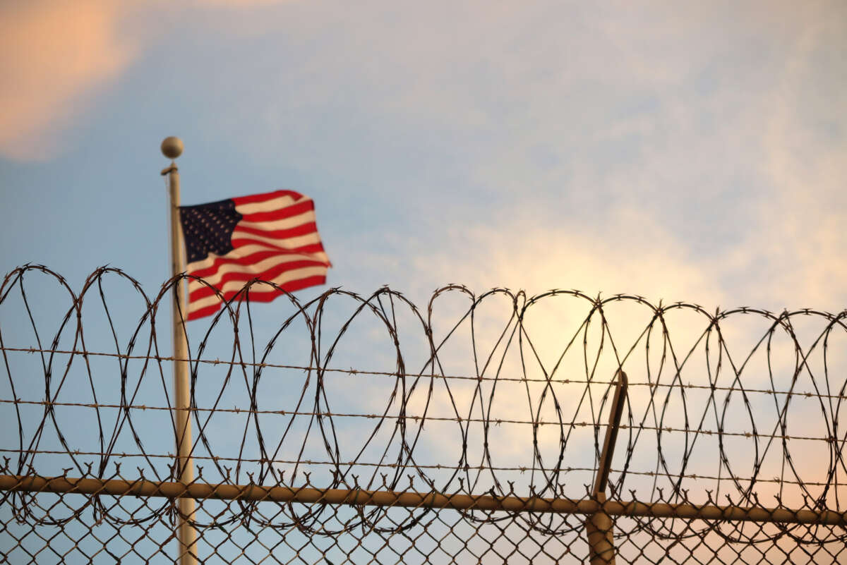 A U.S. flag blows behind a barbed wire fence in the wind at Guantanamo Bay, Cuba, on October 16, 2018.