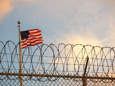 A U.S. flag blows behind a barbed wire fence in the wind at Guantanamo Bay, Cuba, on October 16, 2018.