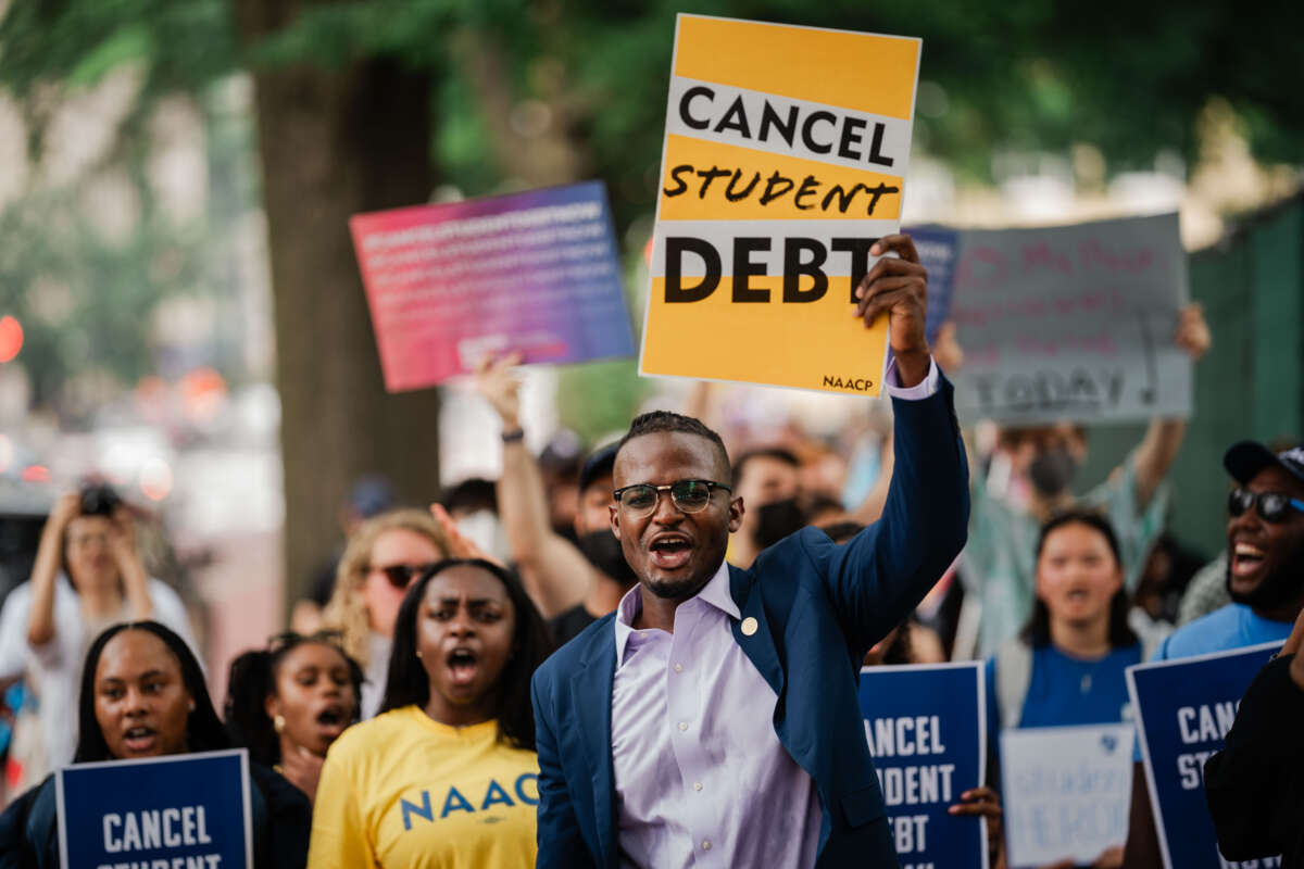 Activists outside the White House hold signs saying "Cancel Student Debt"