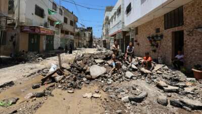 People sit amid the rubble along a street in the occupied West Bank Jenin refugee camp on July 6, 2023, following a large-scale Israeli military raid that lasted for two days.