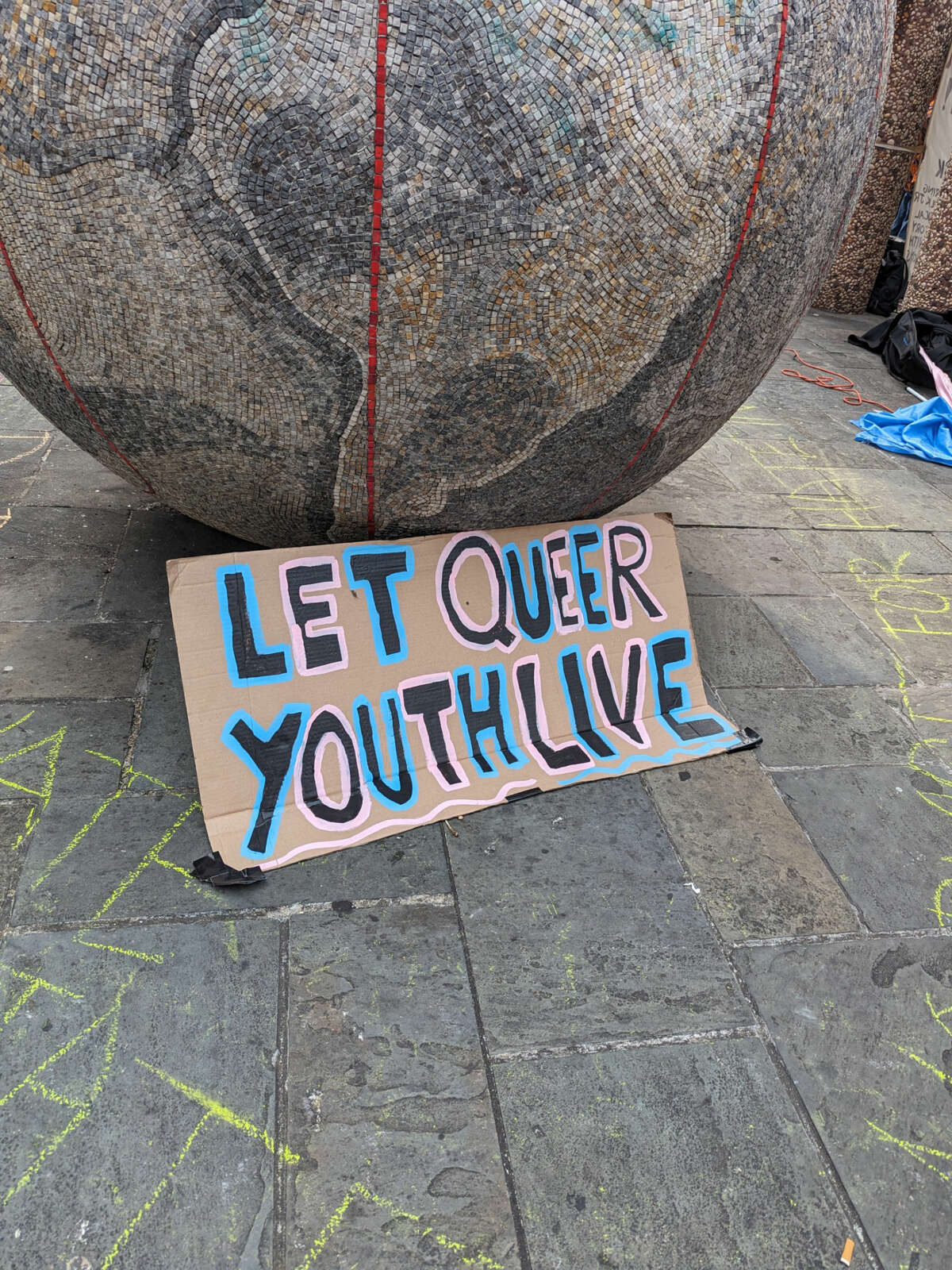 A sign reading "Let Queer Youth Live" leans against a public sculpture near the Marriott hotel in Philadelphia on June 30, 2023.