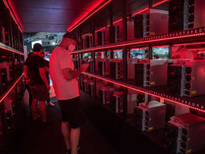 A visitor seen inside a room with crypto miner computers illuminated in red at the MiningPro booth during Thailand Crypto Expo 2022 at Bangkok International Trade & Exhibition Centre (BITEC).