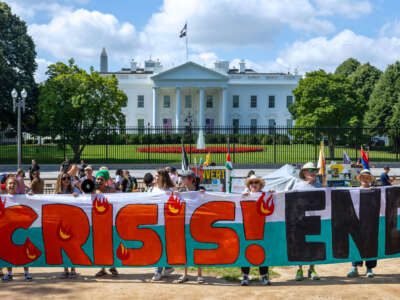 Climate activists chant as they occupy Lafayette Park with a 120 foot banner demanding President Biden act on climate change near the White House on July 4, 2023, in Washington, D.C.