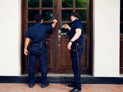 Rear view of police agents with a search warrant arriving to do a home investigation looking for criminal evidence