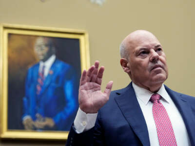 Louis DeJoy raises his hand to swear an oath