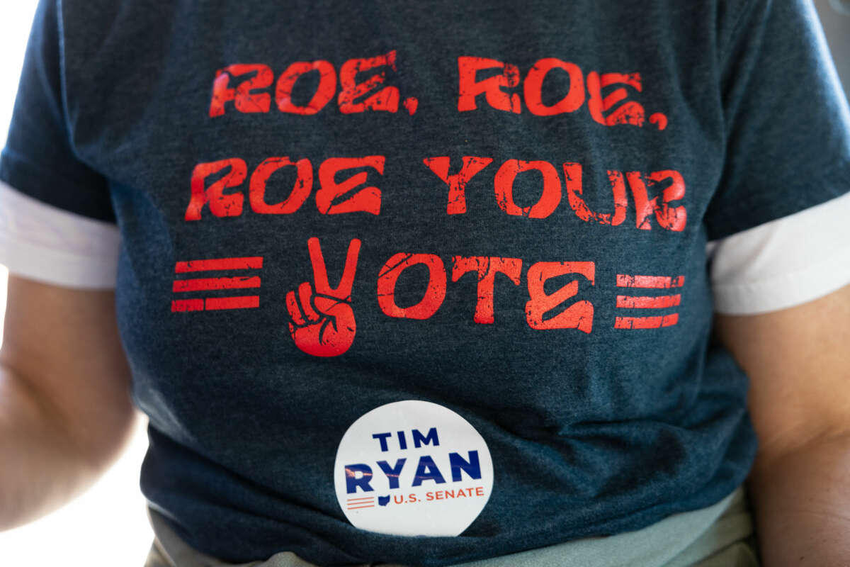 An election worker wears a shirt that reads "ROE ROE ROE YOUR VOTE"