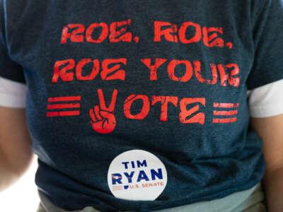 An election worker wears a shirt that reads "ROE ROE ROE YOUR VOTE"