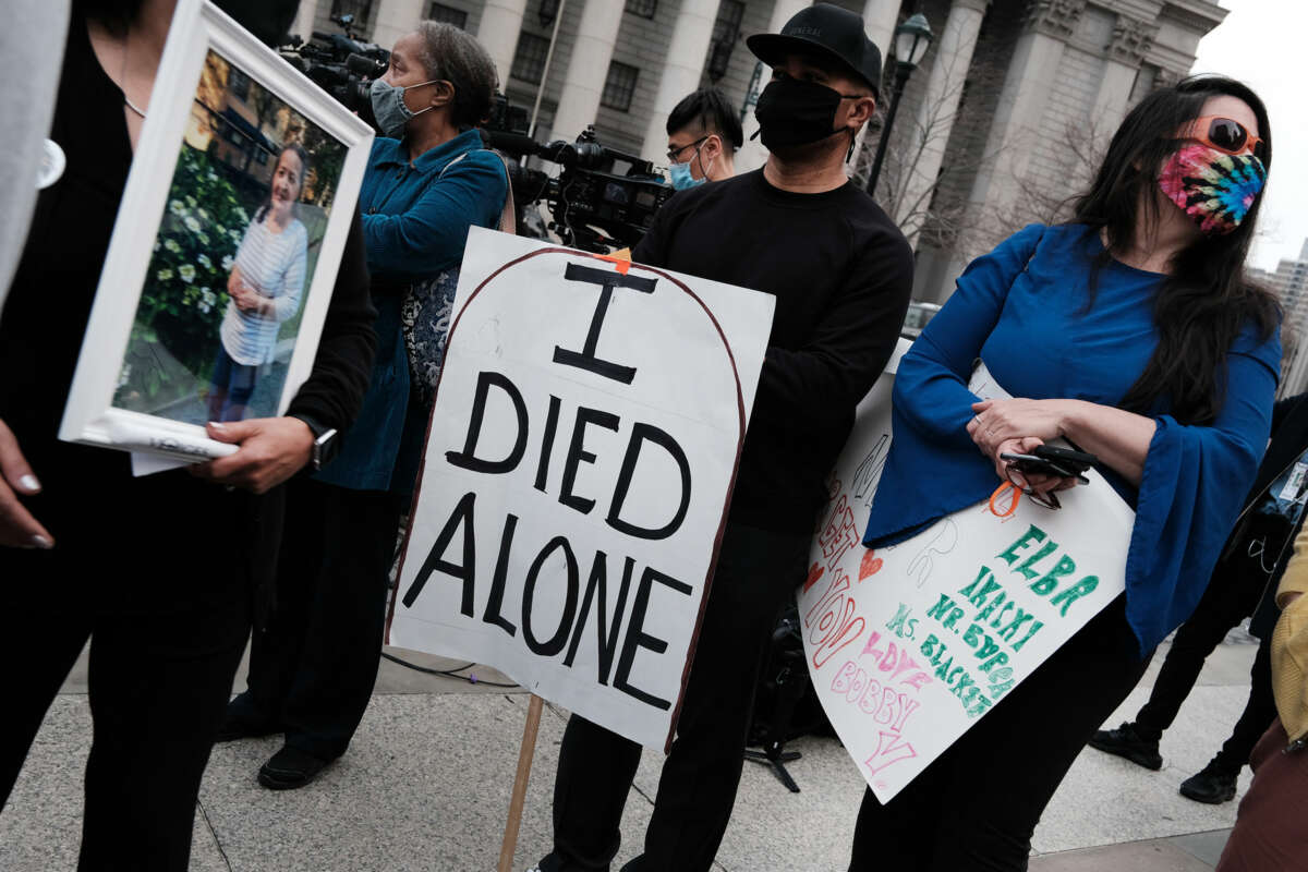 A person holds a sign reading "I DIED ALONE" during an outdoor demonstration to call attention to the plight of seniors in nursing home care during the covid-19 pandemic