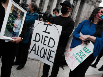 A person holds a sign reading "I DIED ALONE" during an outdoor demonstration to call attention to the plight of seniors in nursing home care during the covid-19 pandemic