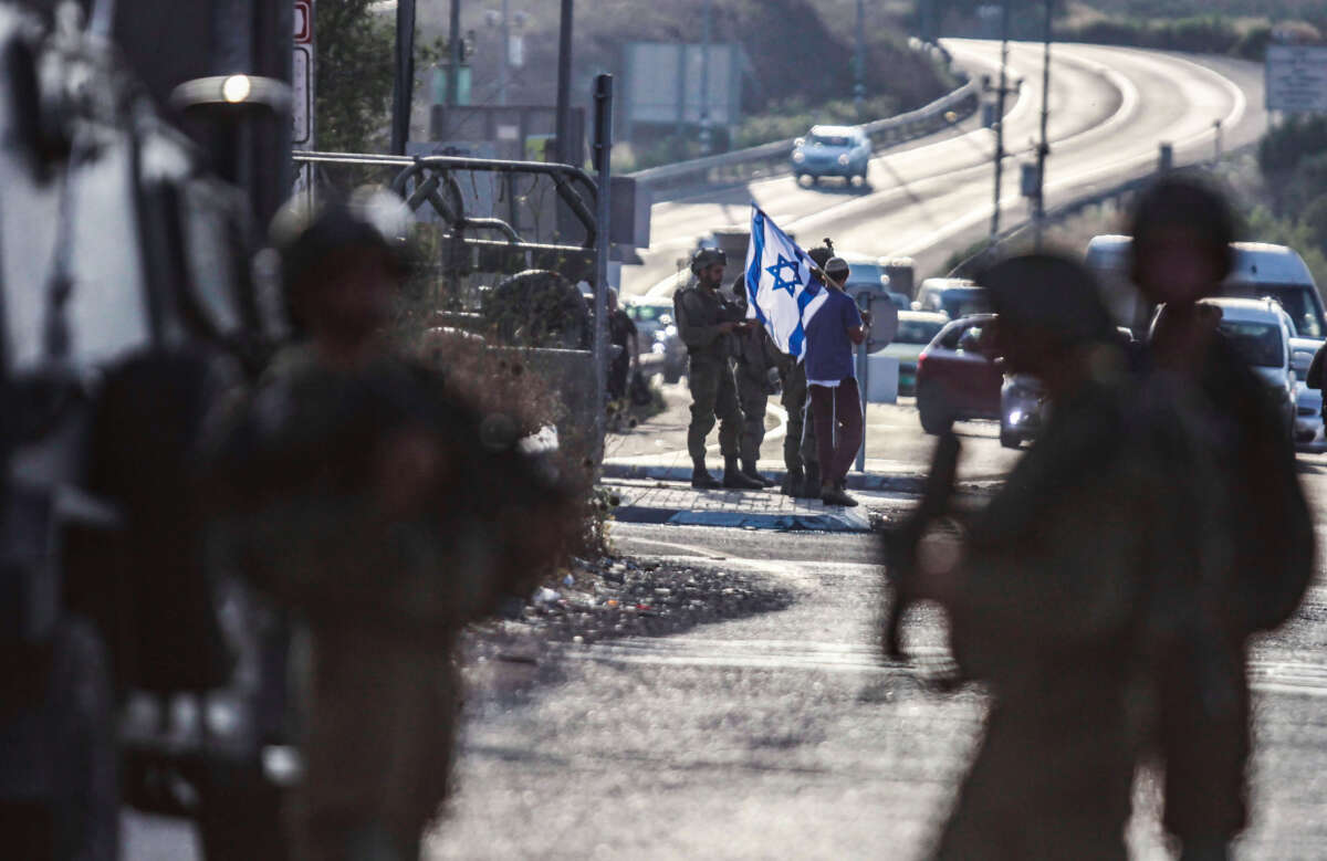 Jewish settlers demonstrate with Israeli flags and block the road in front of Palestinians in Nablus, West Bank, on July 6, 2023.