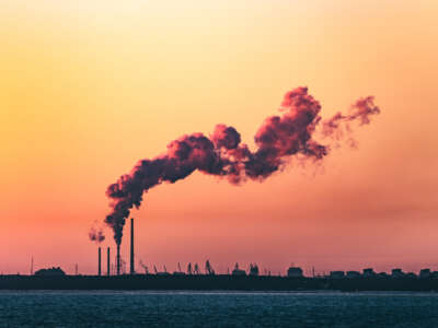 Smoke emissions are pictured over a body of water and sunset