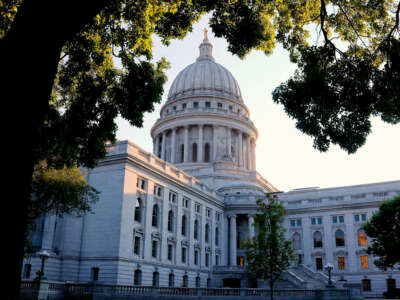 An exterior view of the Wisconsin State Capitol, as seen from behind a large tree