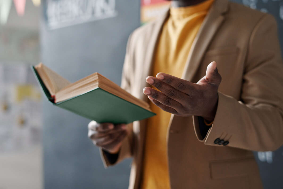 Close-up of African American teacher reading a book for students during a lecture