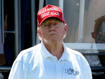 Donald Trump wears a red "MAKE AMERICA GREAT AGAIN" hat