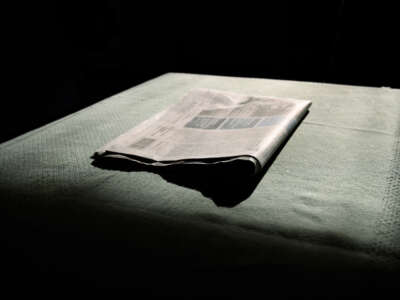 A newspaper sits in darkness