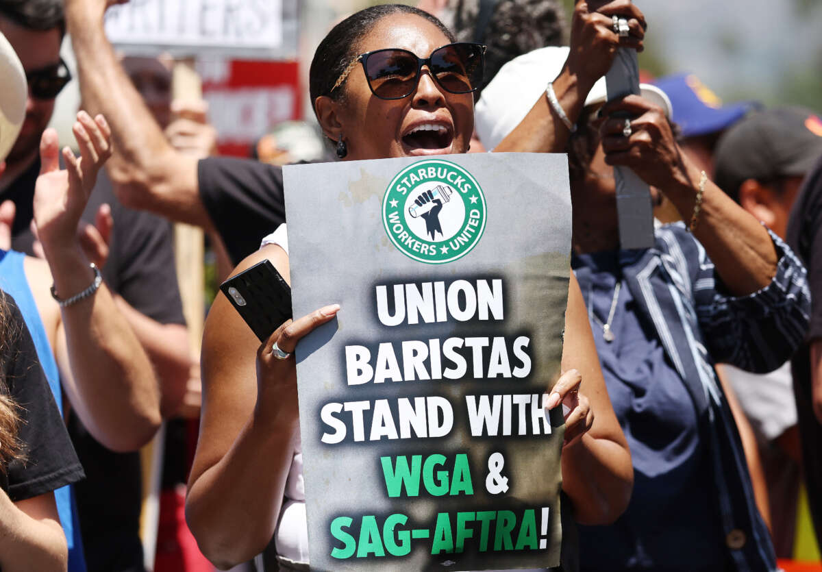 A demonstrator holds a Starbucks union sign as Starbucks workers stand with striking SAG-AFTRA and Writers Guild of America (WGA) members on the picket line in solidarity outside Netflix studios on July 28, 2023, in Los Angeles, California.
