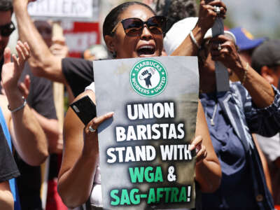 A demonstrator holds a Starbucks union sign as Starbucks workers stand with striking SAG-AFTRA and Writers Guild of America (WGA) members on the picket line in solidarity outside Netflix studios on July 28, 2023, in Los Angeles, California.