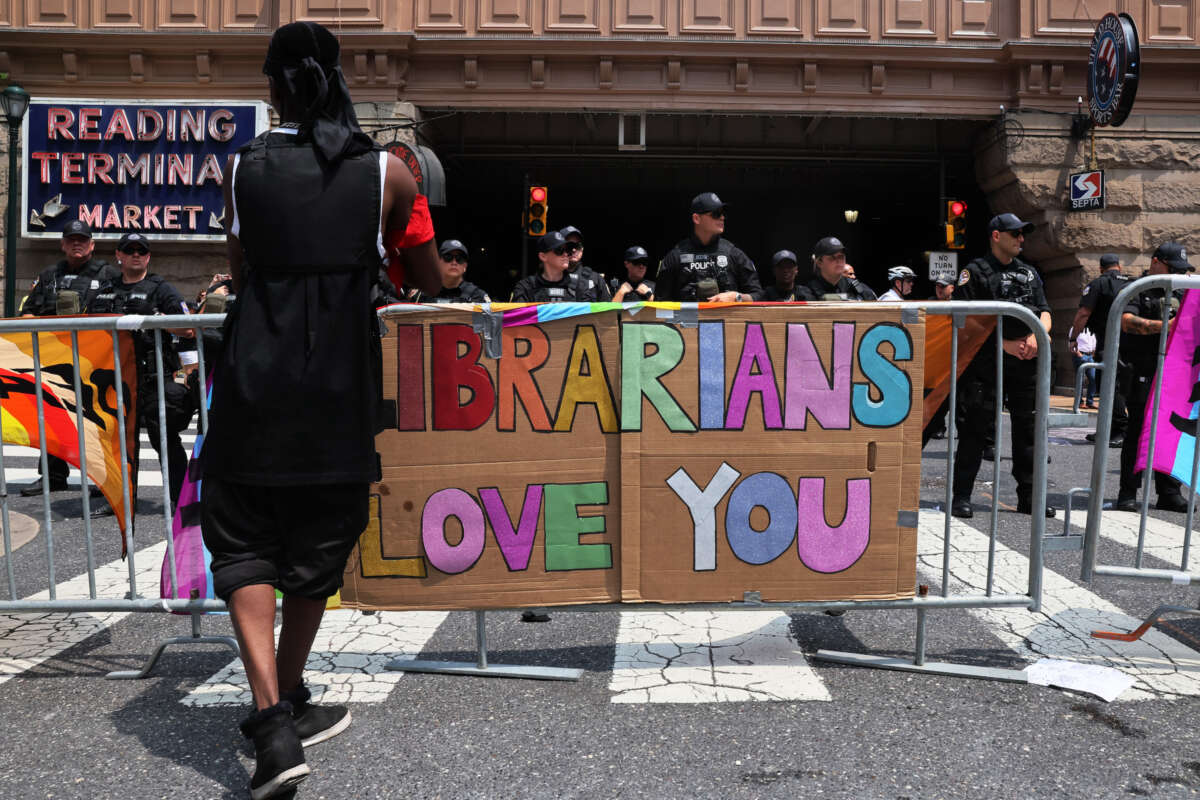 A protest sign reads "Librarians Love You" as Philadelphia police officers guard the Moms For Liberty "Joyful Warriors" national summit outside the Philadelphia Marriott Downtown.