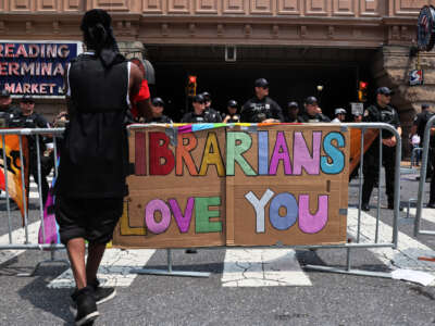 A protest sign reads "Librarians Love You" as Philadelphia police officers guard the Moms For Liberty "Joyful Warriors" national summit outside the Philadelphia Marriott Downtown.
