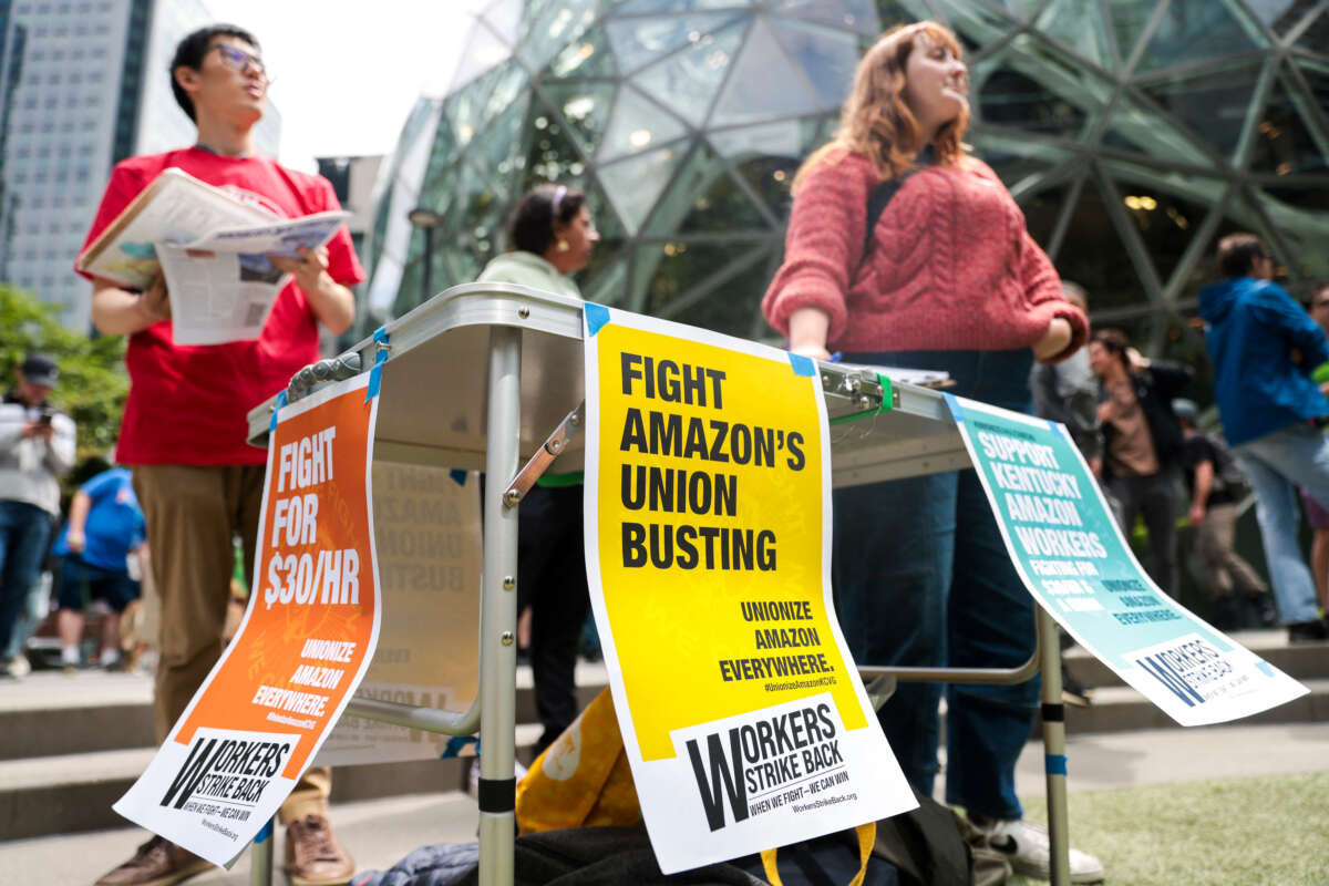 Members of the pro-union group Workers Strike Back look on as Amazon employees and supporters gather during a walk-out protest against recent layoffs, a return-to-office mandate, and the company's environmental impact, outside Amazon headquarters in Seattle, Washington, on May 31, 2023.