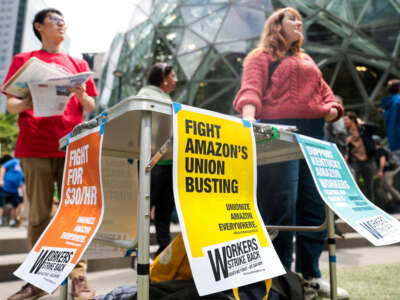 Members of the pro-union group Workers Strike Back look on as Amazon employees and supporters gather during a walk-out protest against recent layoffs, a return-to-office mandate, and the company's environmental impact, outside Amazon headquarters in Seattle, Washington, on May 31, 2023.