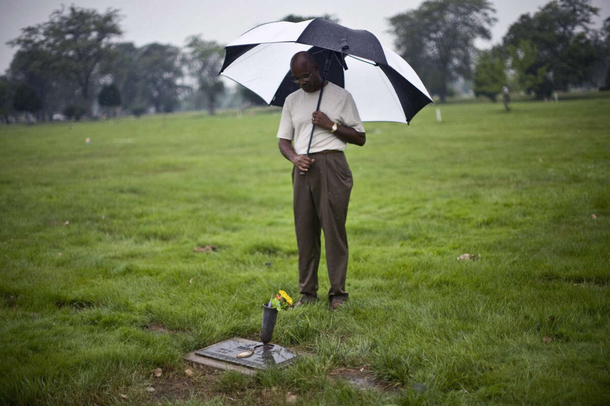 A man with an umbrella pays his respects at Emmitt Till's grave site