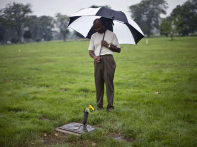 A man with an umbrella pays his respects at Emmitt Till's grave site