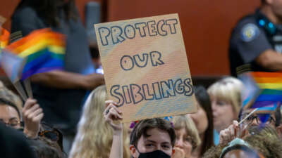 A person holds a sign in opposition to a policy that the Chino Valley school board is meeting to vote on which would require school staff to "out" students to their parents if they ask to be identified by a gender that is not listed on their birth certificate on July 20, 2023, in Chino, California.