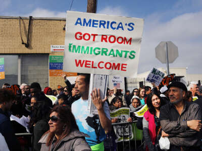A man holds a sign reading "AMERICA'S GOT ROOM; IMMIGRANTS WELCOME" during an outdoor protest