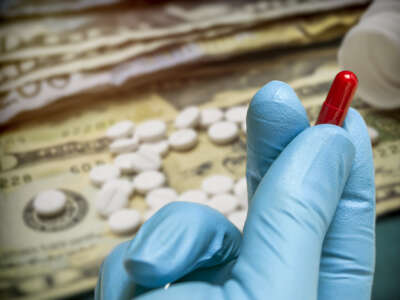 A gloved hand holds a pill capsule with money in the background