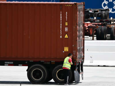 A truck driver inspects a cargo shipping container before departing the Port of Los Angeles in Los Angeles, California on June 7, 2023.