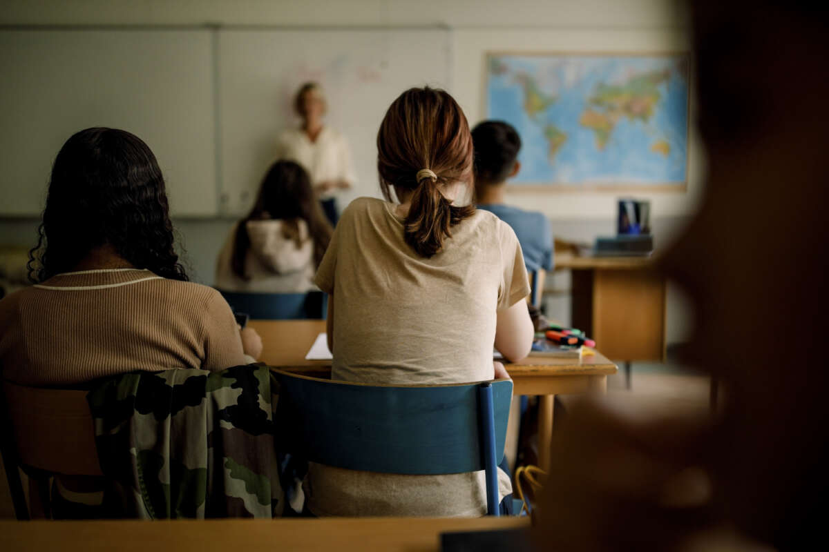 Teenage girl sitting at desk in high school classroom
