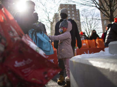 A girl receives a Christmas gift during a giveaway organized by Food Bank For New York City at Highbridge Houses in the Bronx on December 19, 2020, in New York City.