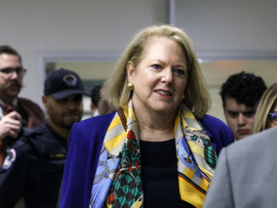 Ginni Thomas, a white woman with short blond hair walks in a crowd of people.