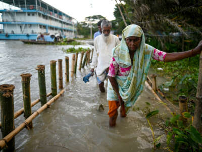 A woman walks through shin-deep floodwater, along with several others