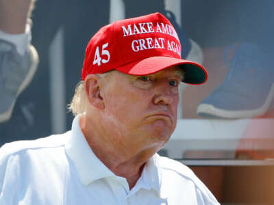 Donald Trump, wearing a Make America Great Again hat, looks bewildered by something occurring out of frame