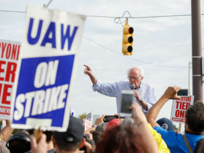 Bernie Sanders speaks passionately to rallying United Auto Worker members, one of whom are holding signs reading "UAW ON STRIKE"