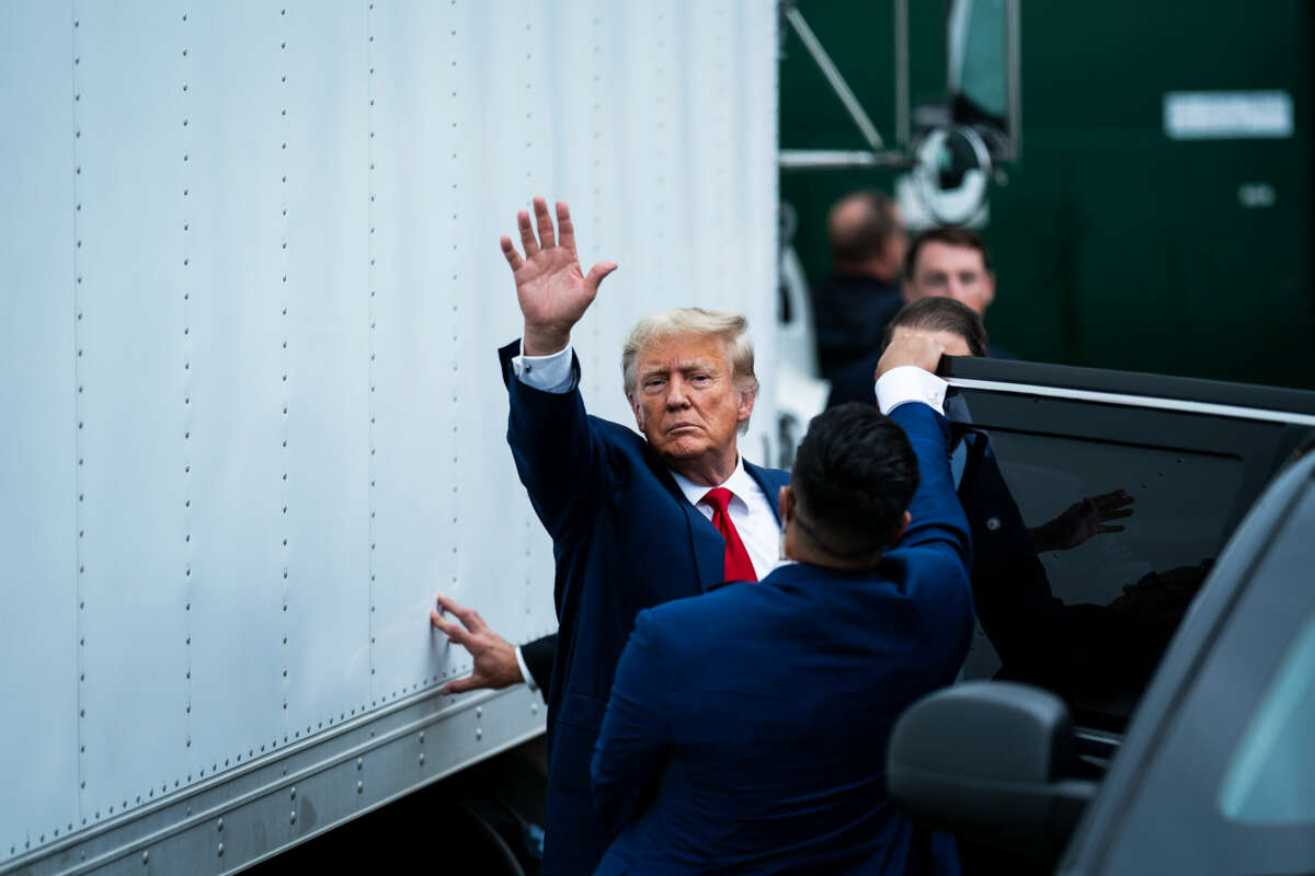 Donald Trump waves while entering a car