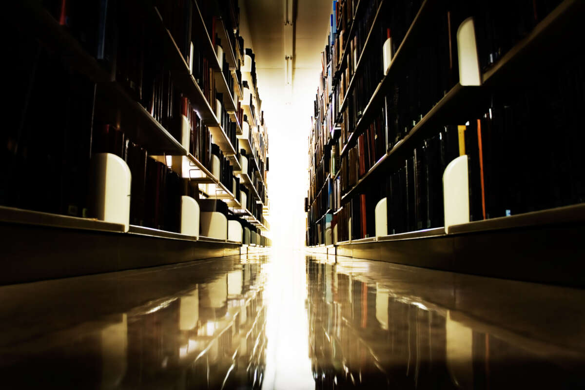 Library bookshelves, dark aisle leading to light