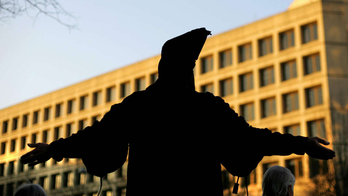 A human rights activist, dressed to resemble the now infamous Abu Ghraib prison photo depicting an Iraqi prisioner being tortured, stands on a street corner during rush hour in front of the U.S. Department of Justice on February 22, 2005, in Washington, D.C.