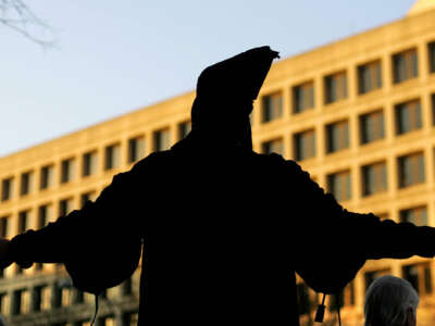 A human rights activist, dressed to resemble the now infamous Abu Ghraib prison photo depicting an Iraqi prisioner being tortured, stands on a street corner during rush hour in front of the U.S. Department of Justice on February 22, 2005, in Washington, D.C.