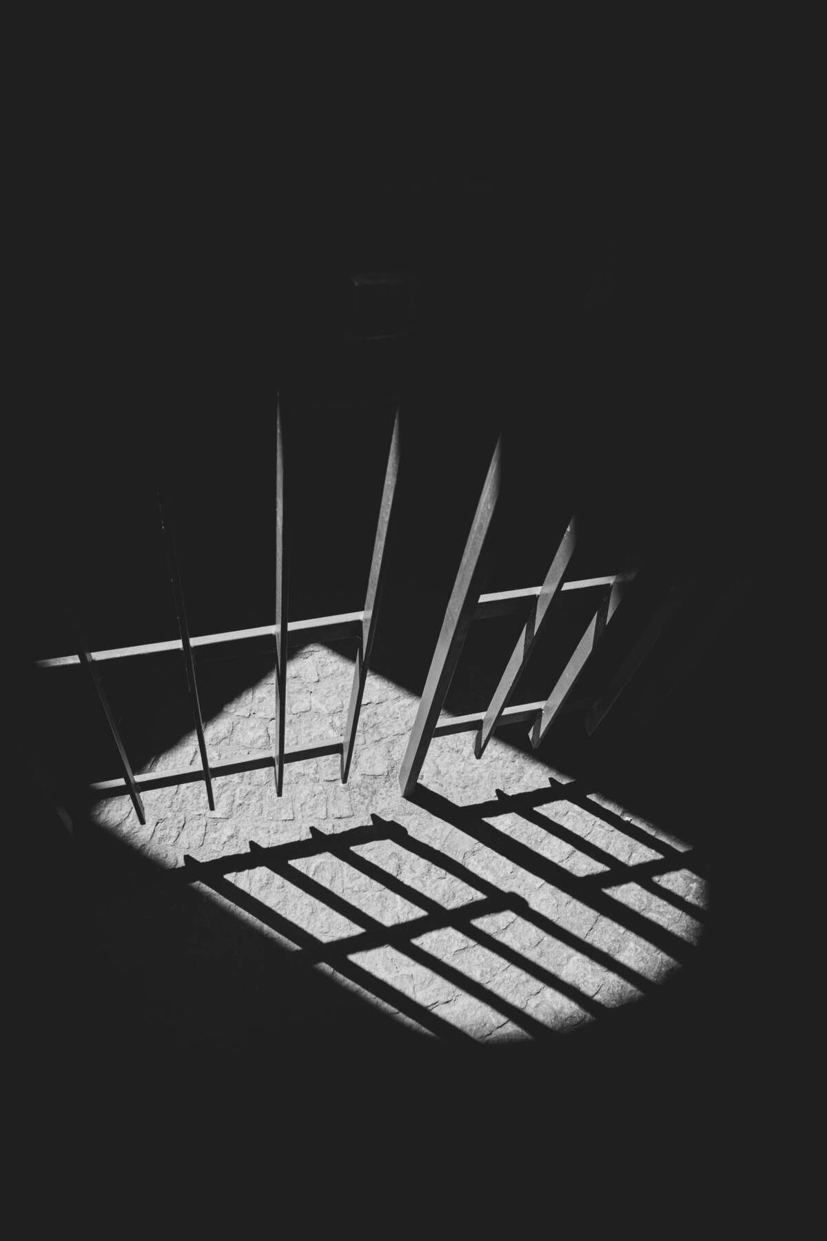 Prison bars and door under spotlight in black and white