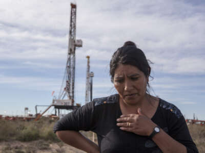 Mabel Izaza, a member of the Indigenous Mapuche ethnic group demanding environmental damage from oil companies, stands in front of a fracking rig at Vaca Muerta on September 15, 2014, in Añelo, Argentina.