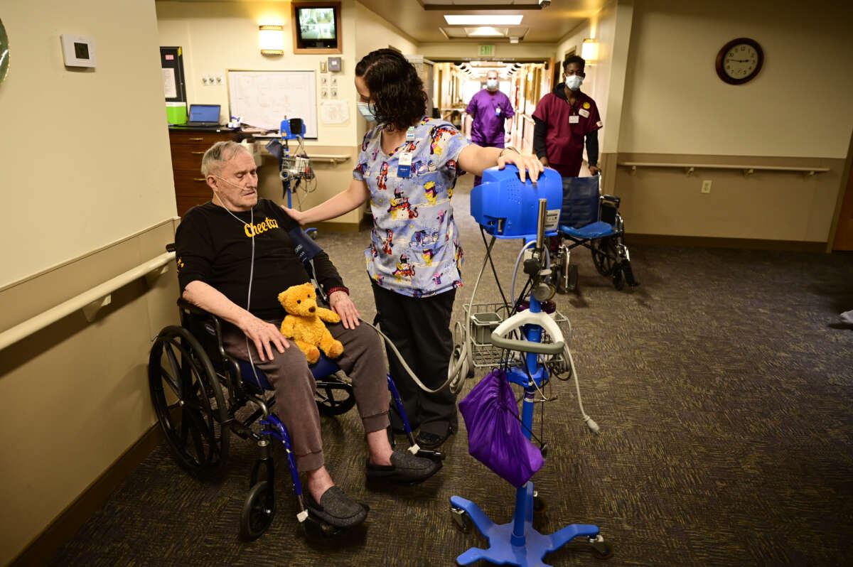 Caregiver Jessica Duarte, right, checks blood pressure of Charles Perkins, 85, at Good Samaritan Society nursing home in Loveland, Colorado on March 4, 2022.