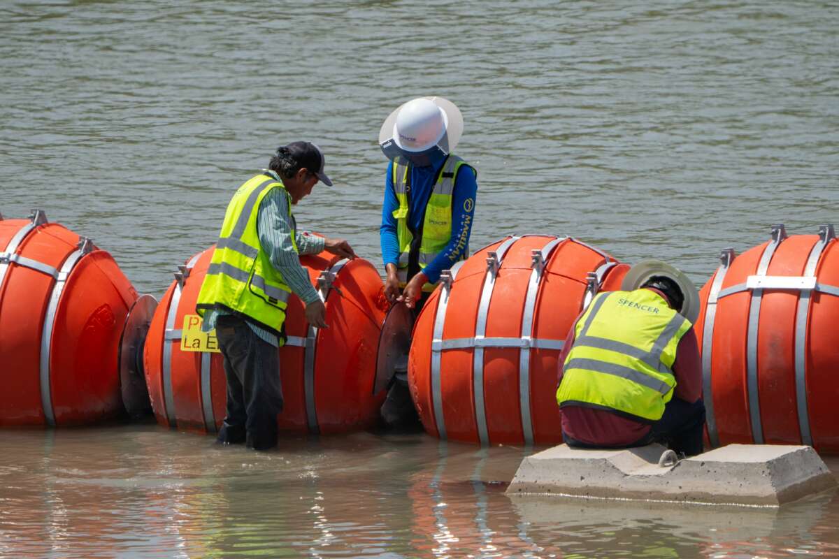 Workers provide maintenance to the blades between the buoys placed along the Rio Grande border with Mexico to prevent migrants from entering the U.S. in Eagle Pass, Texas, on August 25, 2023.